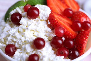 Bowl of cottage cheese with strawberry and cranberry on table, closeup