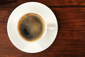 Cup of fresh coffee on wooden table, top view