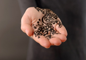 Closeup image of henna on female hand on dark background