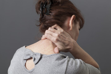 mature woman massaging her backbone for relief