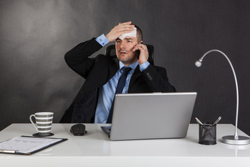 Businessman holding forehead in office.