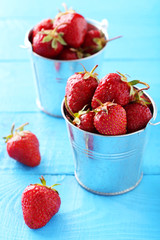 Fresh strawberries berry in bucket on blue wooden background