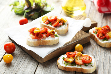 Tasty fresh bruschetta with tomatoes on cutting board on grey wo