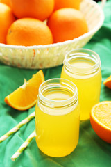 Fototapeta na wymiar Orange juice in bottle and orange in basket on green background