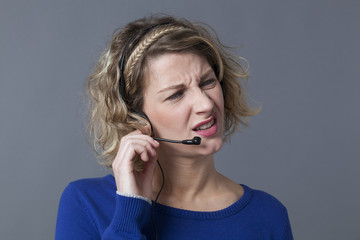 unhappy young callcenter assistant frustrated by difficult phone calls on her headset
