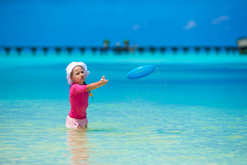 Little girl playing with flying disc at white beach