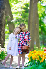 Little adorable girls walking in lush garden of tulips