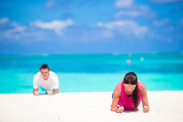 Fototapeta na wymiar Young fitness couple doing push-ups during outdoor cross