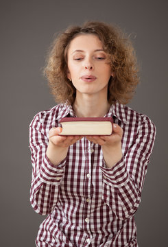 Young Woman Blowing Out Dust Over A Book