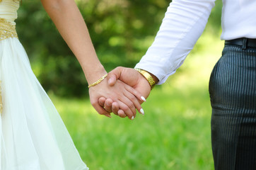 Young couple holding hands on the wedding in summer nature