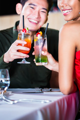 Asian couple drinking cocktails in fancy bar