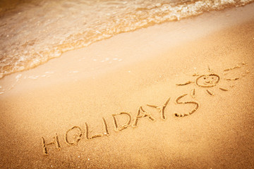 The word holidays written in the sand on a beach