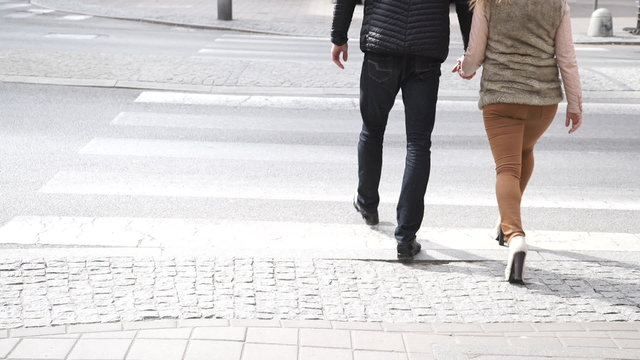Couple holding hands crossing street zebra