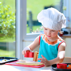 Little happy child, adorable toddler girl in white chef hat helping mother cooking delicious pastry...
