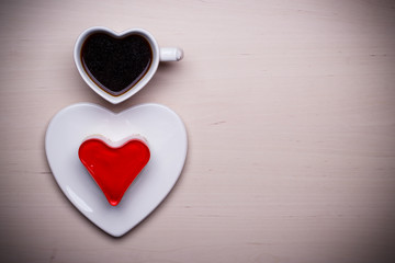 Heart shaped coffee cup and cake on wood surface