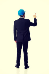 Engineer in protective helmet pointing up.