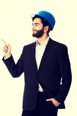 Engineer in protective helmet pointing up.