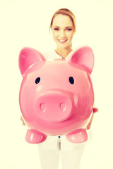 Young female doctor holding a piggybank.