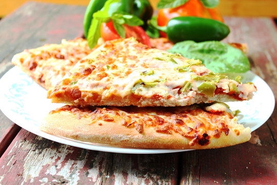pizza slice closeup with green pepper tomato and herb