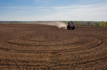 Obraz premium Blue tractor plowing a field before planting