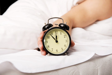 Man with alarm clock in bedroom.