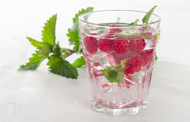 Summer cold drink with raspberries, ice and fresh mint .