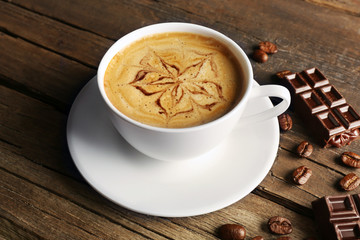 Cup of coffee latte art with grains and chocolate on wooden background