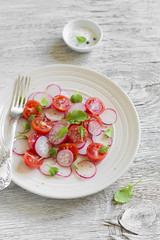 salad with cherry tomatoes and radishes in a white plate 