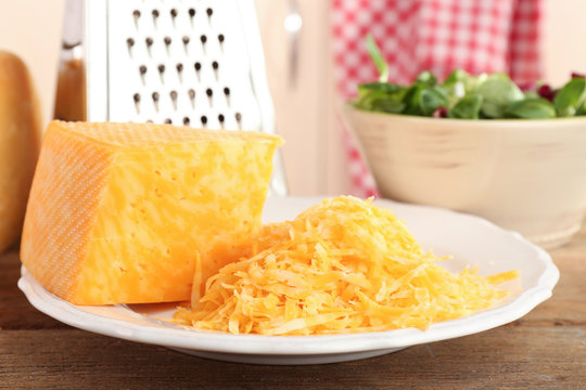 Grated cheese on wooden table in kitchen, closeup
