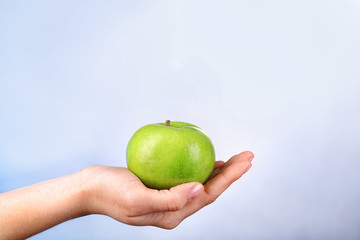 Female hand with apple on colorful background