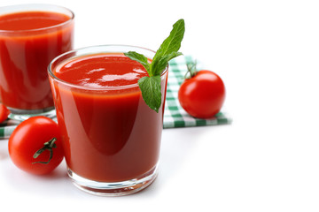 Glasses of fresh tomato juice on checkered napkin, isolated on white