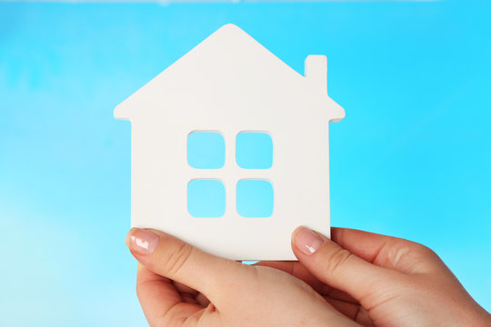 Female hands with model of house on color background