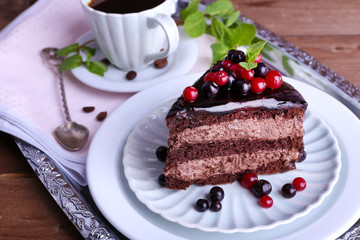 Delicious chocolate cake with berries and cup of coffee on table close up
