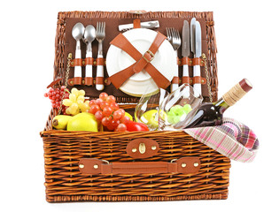 Wicker picnic basket with food, tableware and tablecloth isolated on white