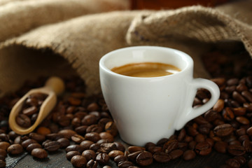 Cup of coffee with beans on table close up