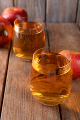 Glasses of apple juice on wooden background