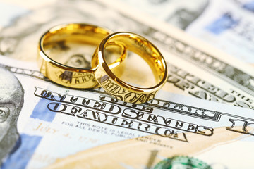 Golden wedding rings on banknotes background. Marriage of convenience