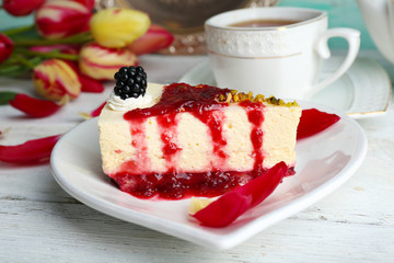 Tasty piece of cheesecake with berry sauce on plate on table close up