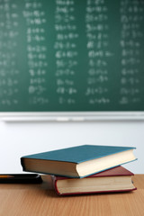 Stack of books on desk, on blackboard background