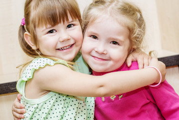 Two happy little girls hugging