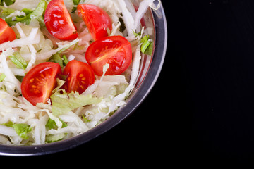 fresh salad in a metal plate on black