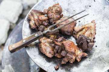 Fried turkey meat on large metal frying pan with a fork