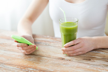 close up of woman with smartphone and green juice