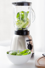 close up of blender jar and green vegetables