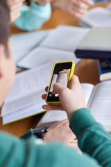 student hands with smartphone making cheat sheet