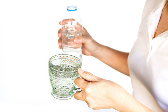 Female hand pouring water into a glass from bottle .