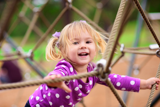 Happy Little Girl Climbing On Outdoor Playground