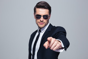 Businessman in sunglasses pointing at camera
