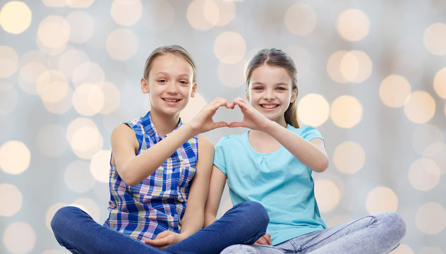 happy little girls showing heart shape hand sign