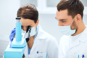 scientists in masks looking to microscope at lab